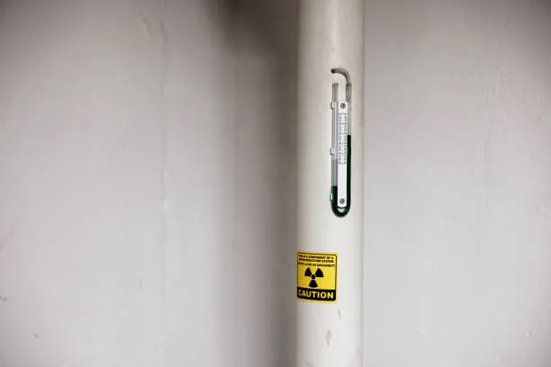 Manometer and caution label on a radon mitigation system vent pipe